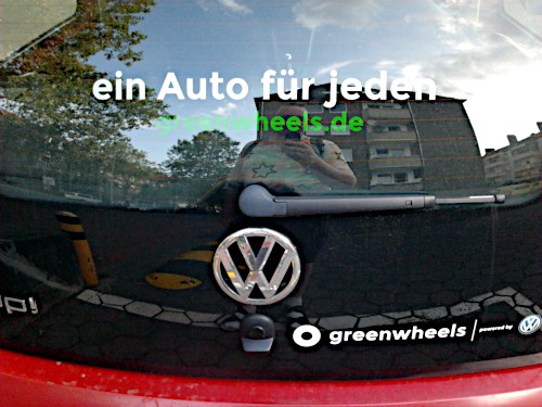 Heckscheibe eines Autos, mit VW-Werbung beklebt: ein Auto für jeden -- greenwheels.de -- greenwheels powered by VW
