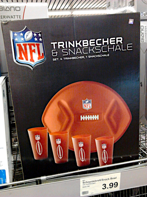 Produktverpackung. NFL-Logo. Trinkbecher und Snackschale. Set: 4 Trinkbecher, 1 Snackschale. Die Schale hat die charakteristische Form eines Football-Balles, auf den Bechern ist ein solcher abgebildet. Alle fünf Teile wurden mit dem Logo der NFL bestempelt.